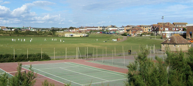 Cricket on the Salts Recreation Ground in Seaford, with a cream scout hut beyond the pitches