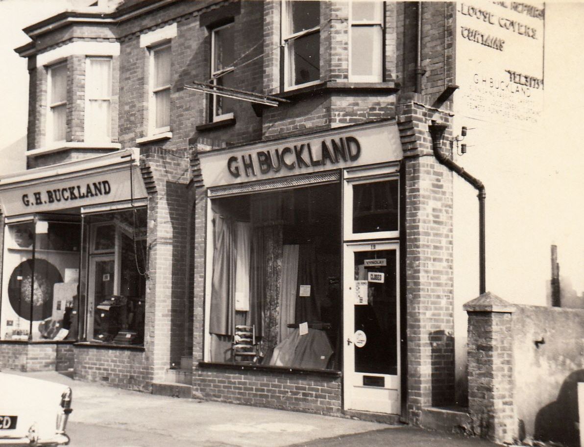 Two shopfronts of G. H. Buckland, interior furnishers, on Sutton Road in Seaford, in a black and white photograph