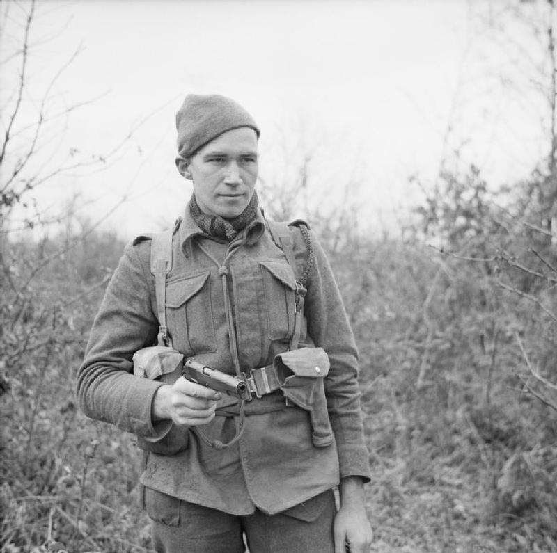 Private W Stack of No. 9 Commando at Anzio holding a Browning pistol, March 1944