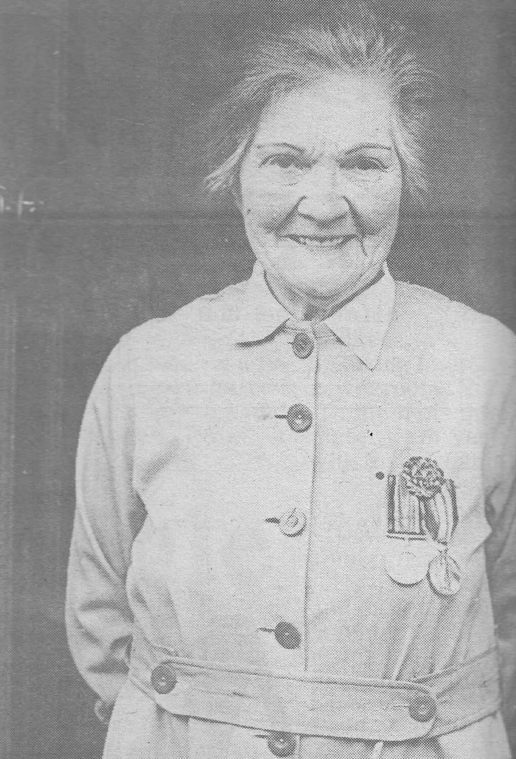 Winifred Mandeville as an elderly woman in 1988, smiling, wearing her First World War khaki coat-frock with two medals pinned to it